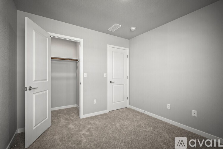 A room with two doors, one of which is open, and a carpeted floor.
