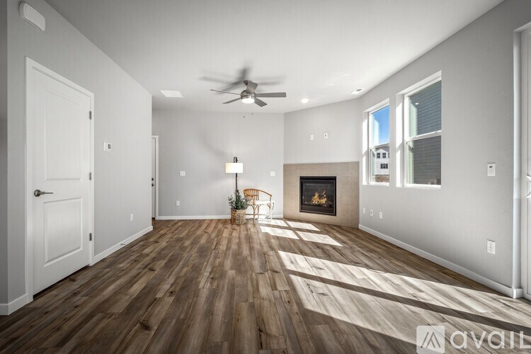 A spacious living room with a fireplace and a ceiling fan.