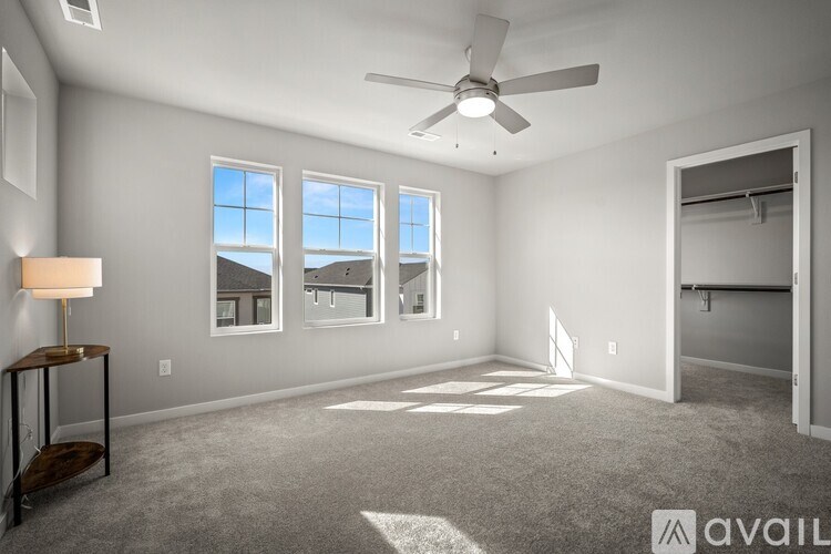 A spacious room with a ceiling fan and large windows.