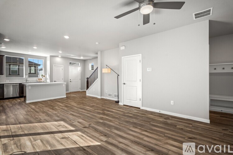 A spacious living room with a ceiling fan and hardwood flooring.