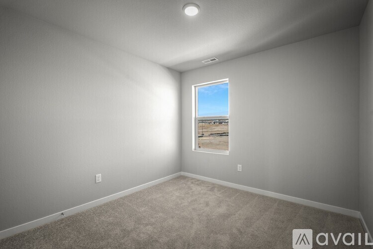 A room with a window showing a view of a field.