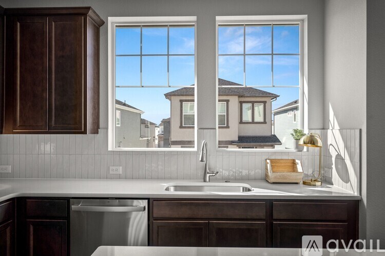 A modern kitchen with a large window overlooking a residential area.
