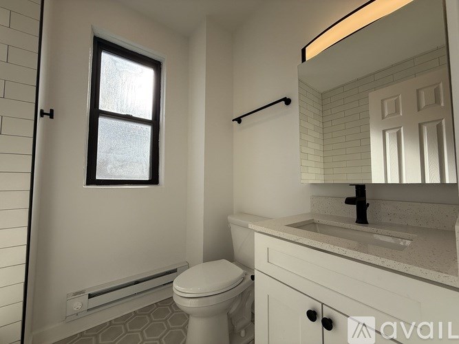A bathroom with a toilet, sink, and a window.