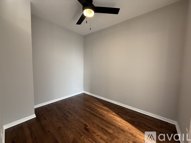 A room with a ceiling fan and wooden flooring.