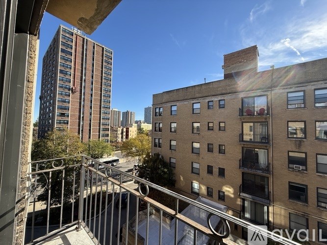 A view from a balcony overlooking a city street with buildings and cars.