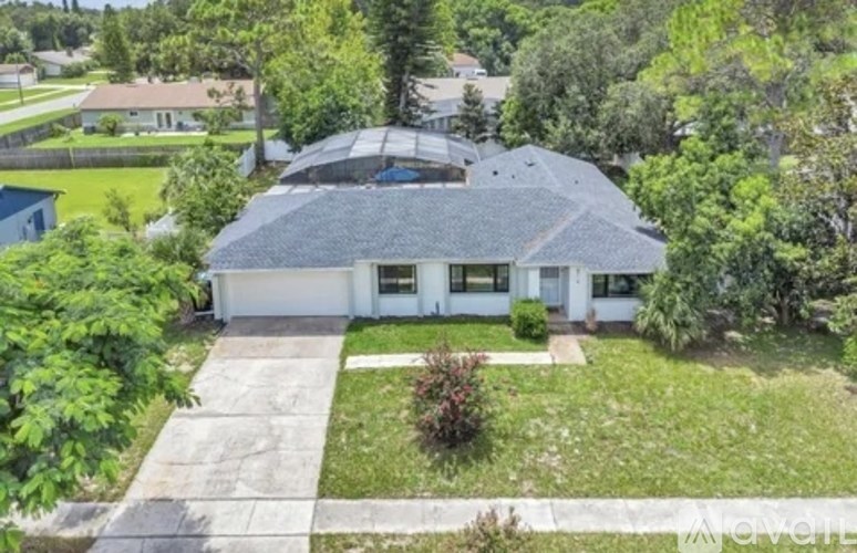 A house with a grey roof and white walls is surrounded by greenery.