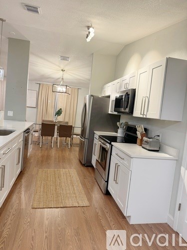A kitchen with white cabinets and a wooden floor.