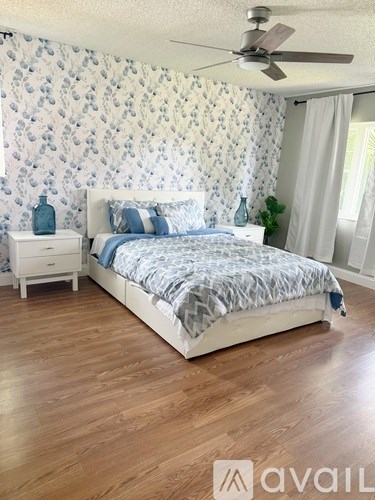 A bedroom with a patterned wallpaper and a bed with a white frame.