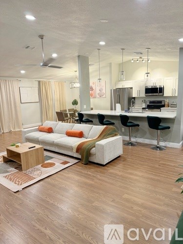A living room with a white couch and a wooden floor.