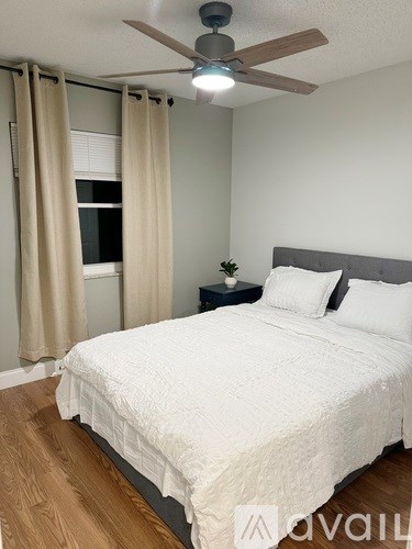 A bedroom with a bed, nightstand, and window with curtains.