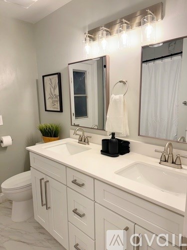 A white bathroom with a toilet, sink, mirror, and lights.