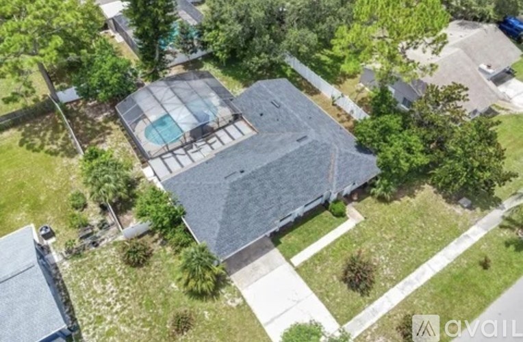 A house with a pool surrounded by trees and a stone pillar.