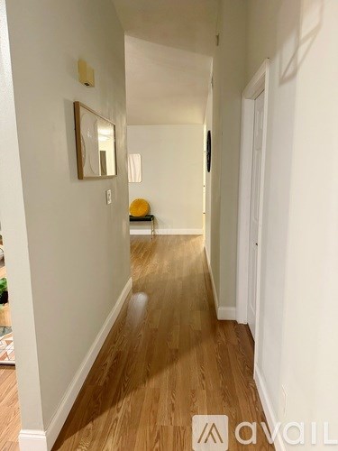 A hallway with wood floors and white walls.