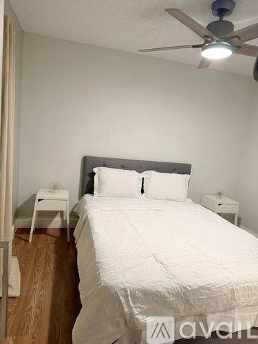 A bedroom with a bed, nightstands, and a ceiling fan.