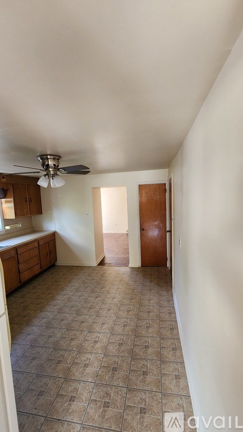 A room with a ceiling fan and tile flooring.