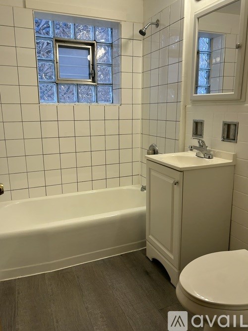 A white bathroom with a tub, toilet, sink, and mirror.