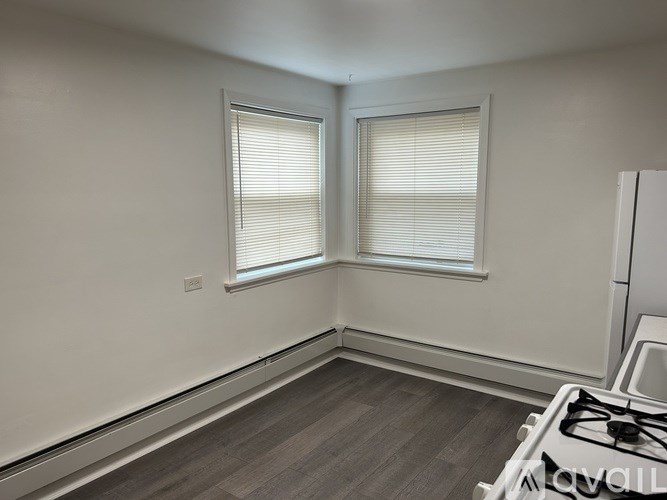 A room with a gas stove and two windows with blinds.