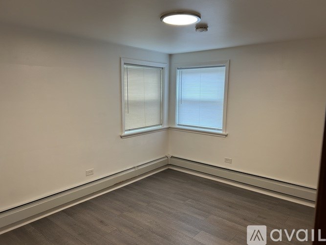 A room with a window and a wooden floor.