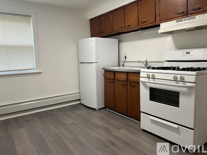 A kitchen with a white fridge, white stove, and wooden cabinets.