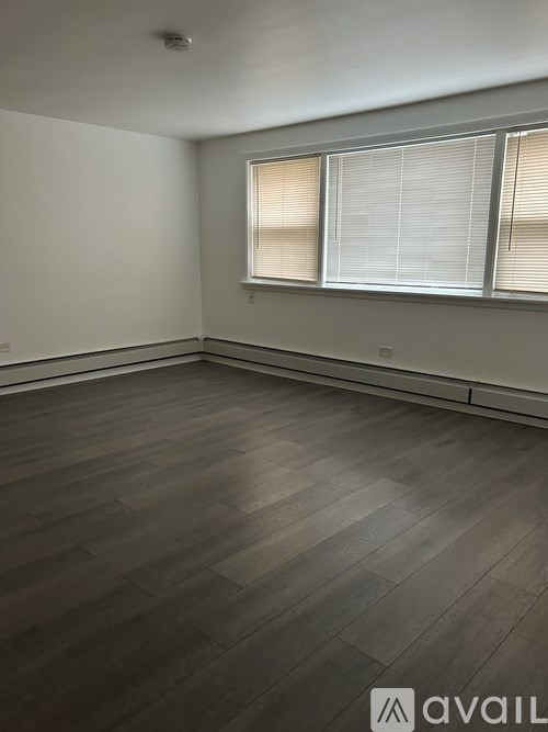 A room with wooden flooring and a window with blinds.