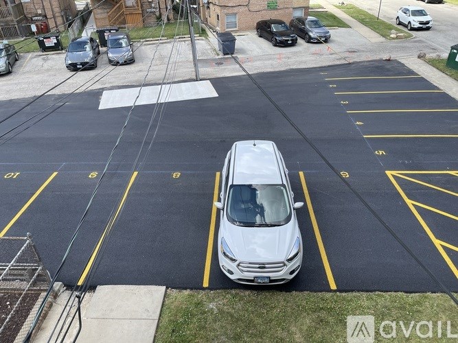 A white car is parked in a parking lot with yellow lines.