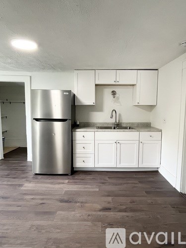 A kitchen with a refrigerator, sink, and cabinets.