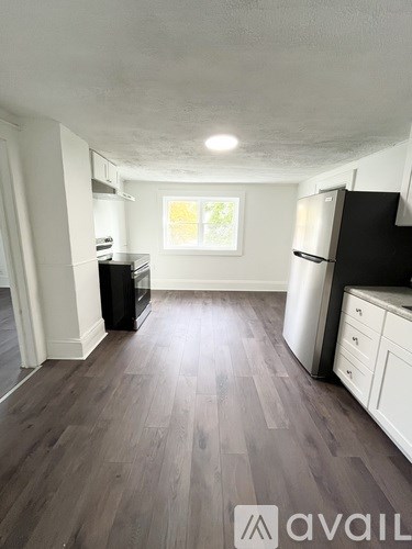 A kitchen with a black fridge and wooden floors.