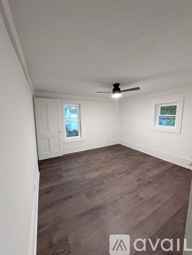A room with wooden flooring and a ceiling fan.