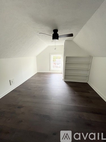 A room with a ceiling fan and wooden flooring.