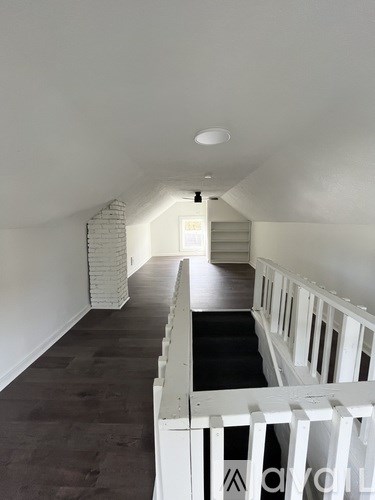 A long hallway with a staircase on the right and a white railing.