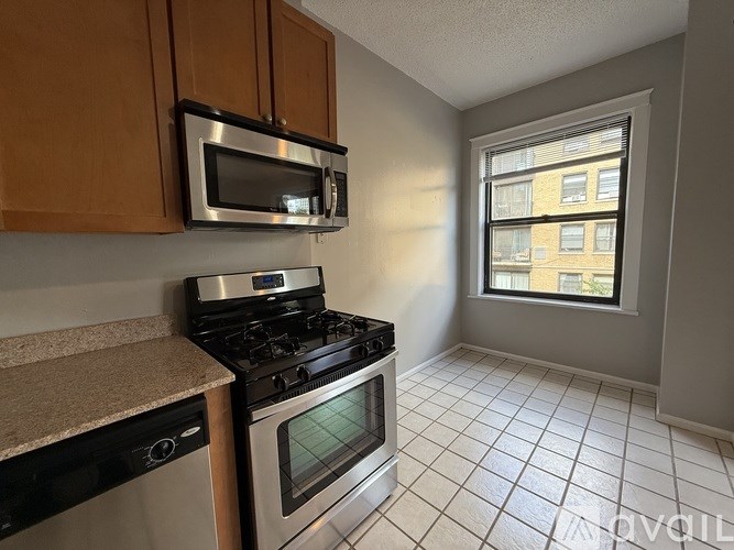 A kitchen with a stove, oven, microwave, and a window.