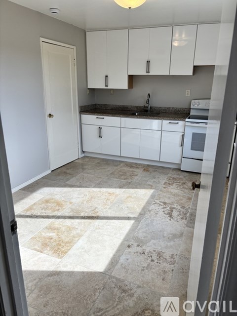 A kitchen with white cabinets and a tiled floor.