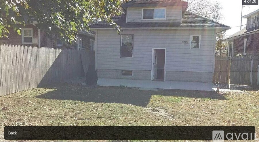 A house with a white siding and a brown door is surrounded by a wooden fence.