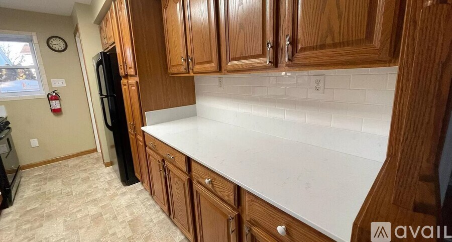 A kitchen with wooden cabinets and a black refrigerator.