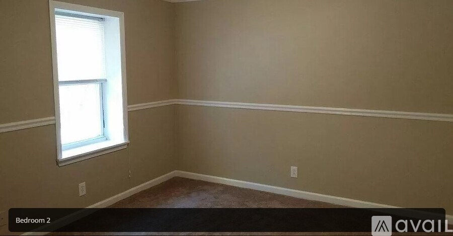 A room with a window and a carpeted floor.