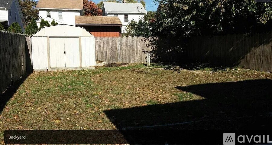 A backyard with a white shed and a wooden fence.