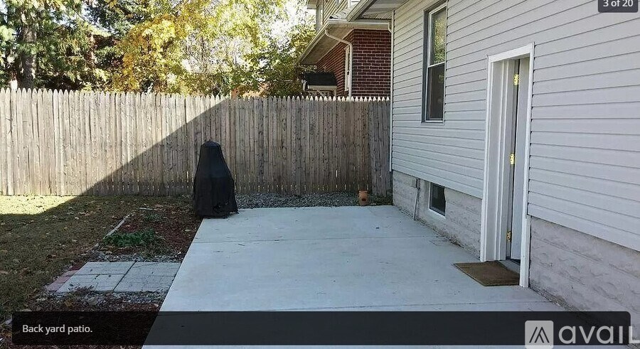 A backyard patio with a concrete floor and a wooden fence.