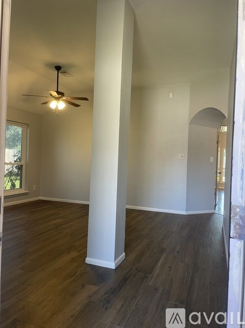 A room with a ceiling fan and wooden floors.