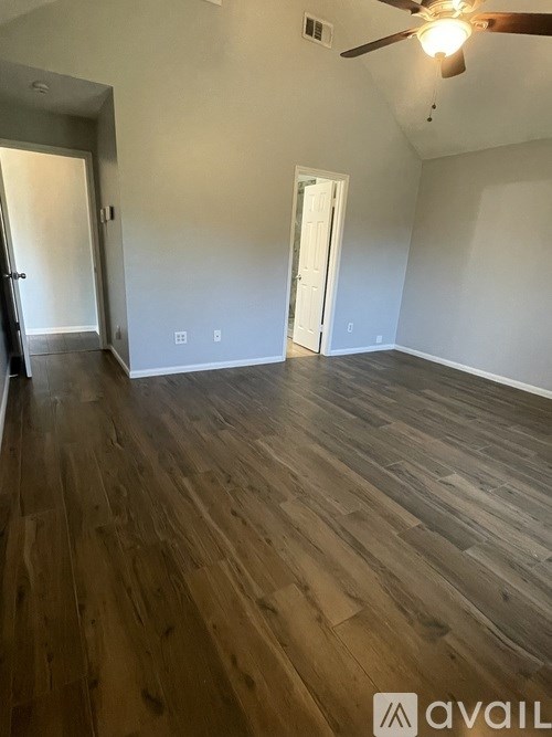 A room with wooden flooring and a ceiling fan.