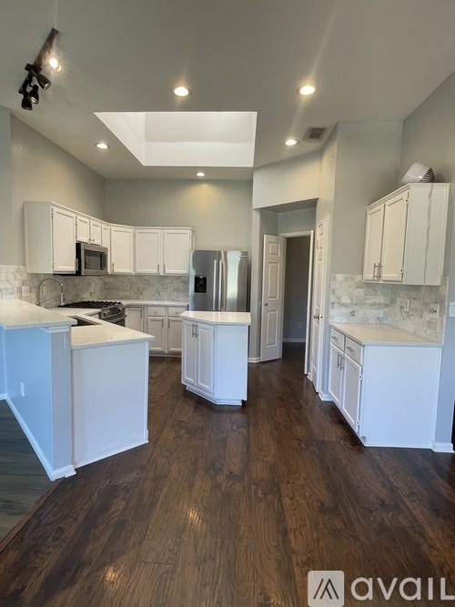 A kitchen with white cabinets and a wooden floor.