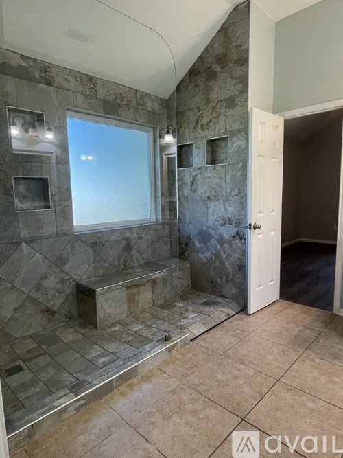 A bathroom with a marble tile shower and a window.