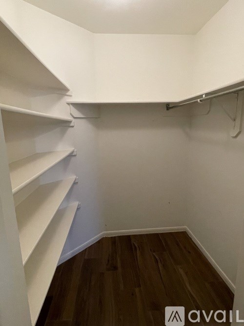 A white closet with wooden shelves and a white wall.