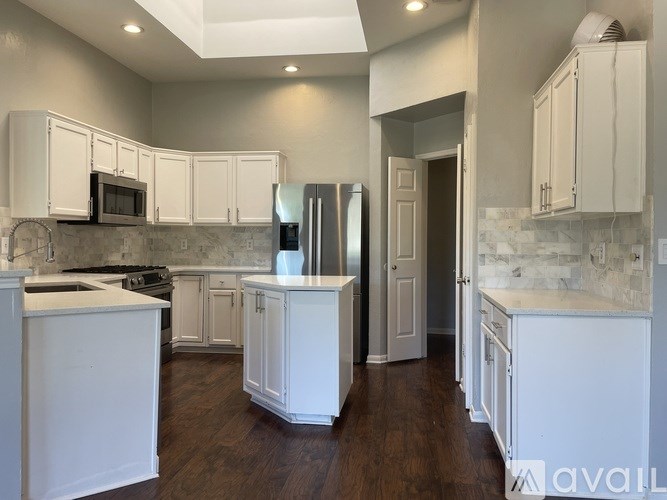 A kitchen with white cabinets and a marble backsplash.