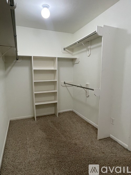 A small, empty room with a carpeted floor and a closet with shelves.