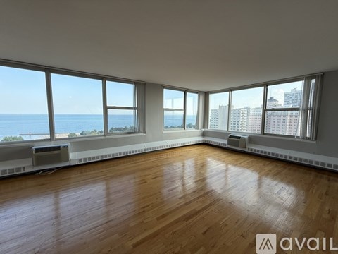 A spacious room with wooden floors and large windows overlooking the city.