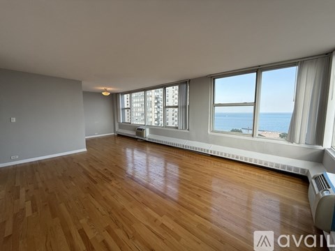 A room with wooden floors and a window overlooking the sea.