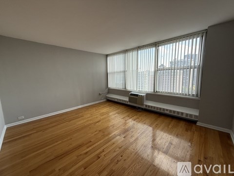 A room with wooden flooring and a window with blinds.