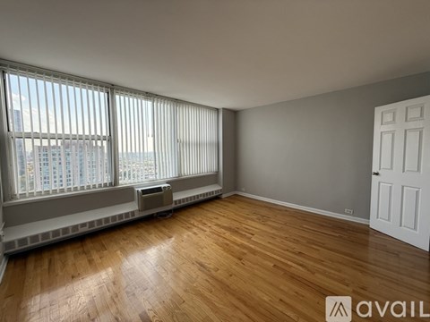 A room with wooden floors and a large window with blinds.