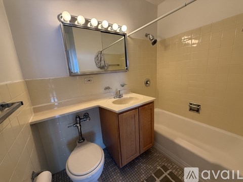 A bathroom with a white toilet, a sink, and a mirror with lights.