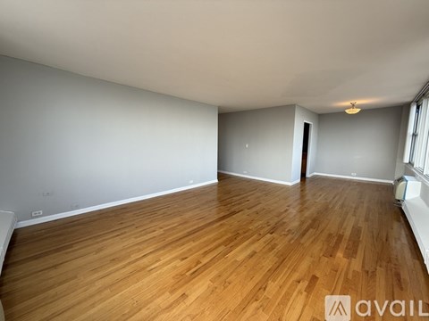 A room with wooden flooring and white walls is available for rent.